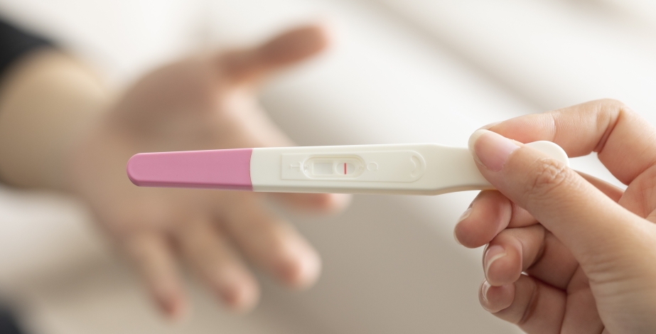 woman holding up pregnancy test kit with negative result